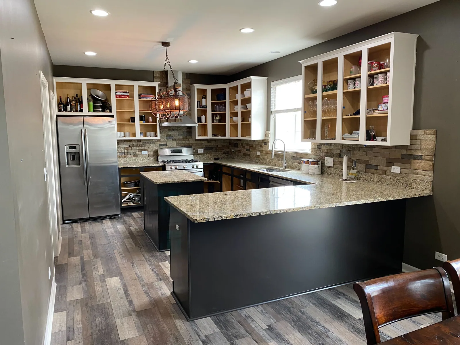 Kitchen with a refinished black island and white perimeter cabinets