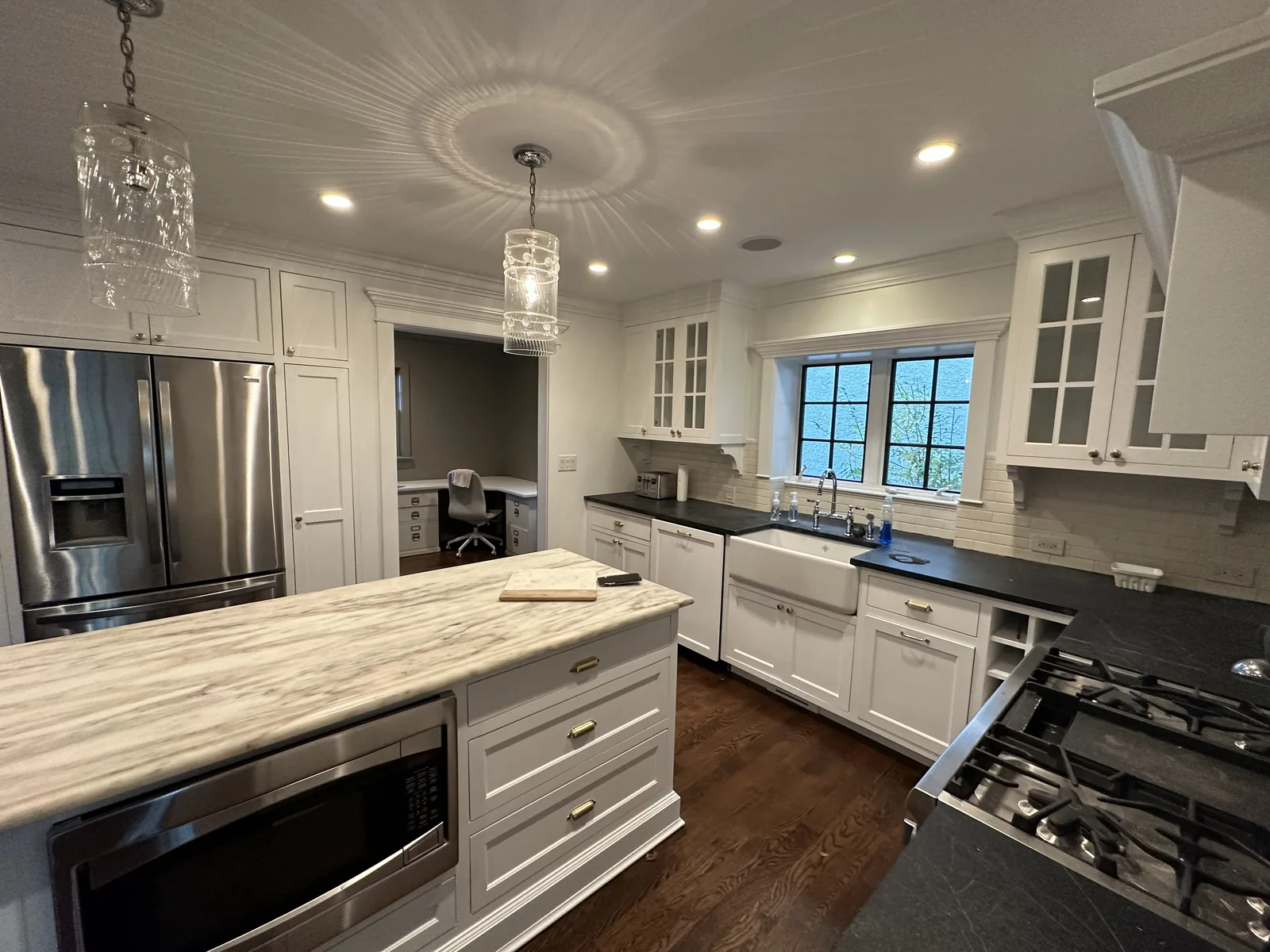 White refinished cabinets with a gray island and glass uppers