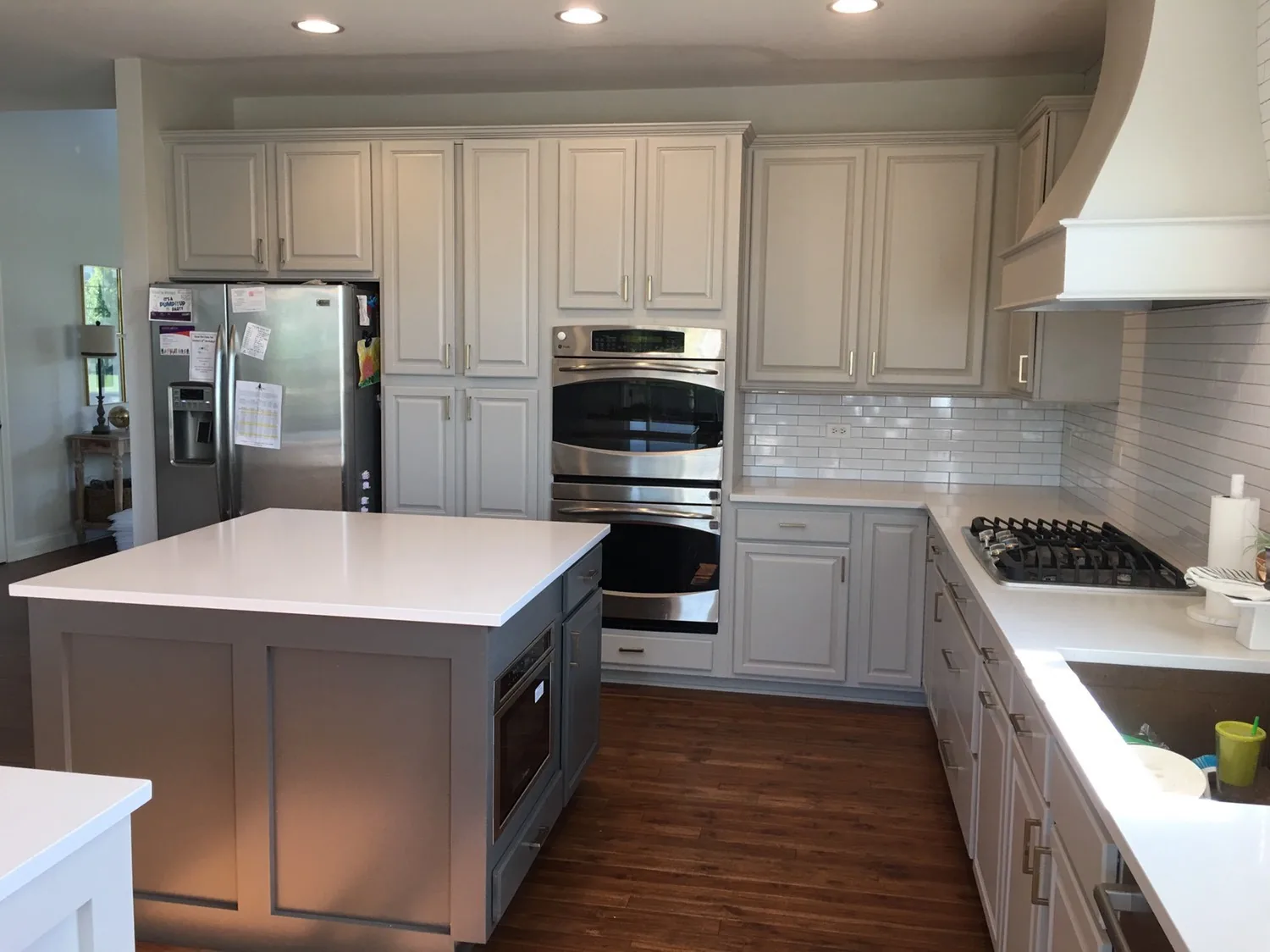 White refinished cabinets with a gray island and double ovens