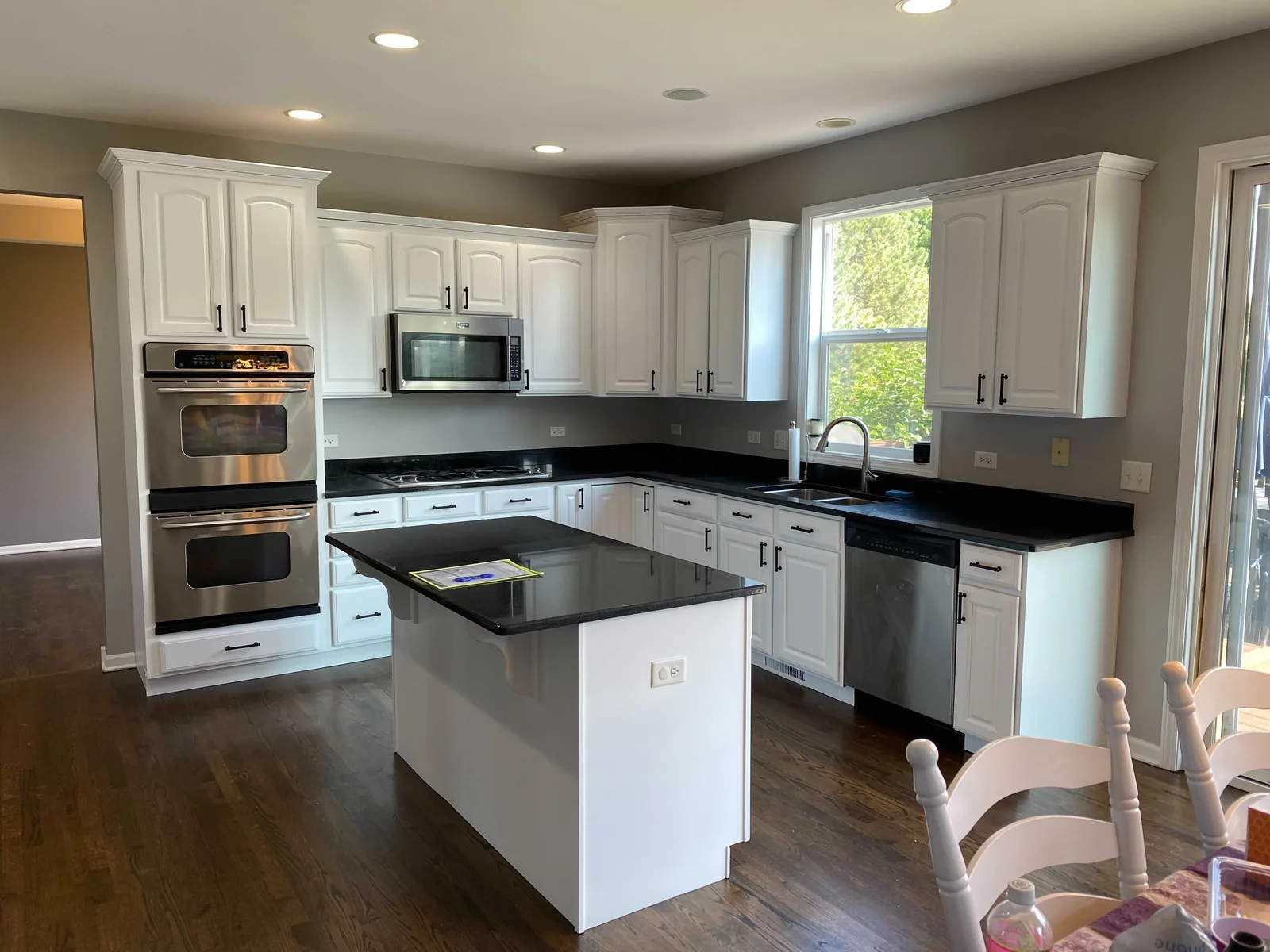 White refinished cabinets with a black countertop island