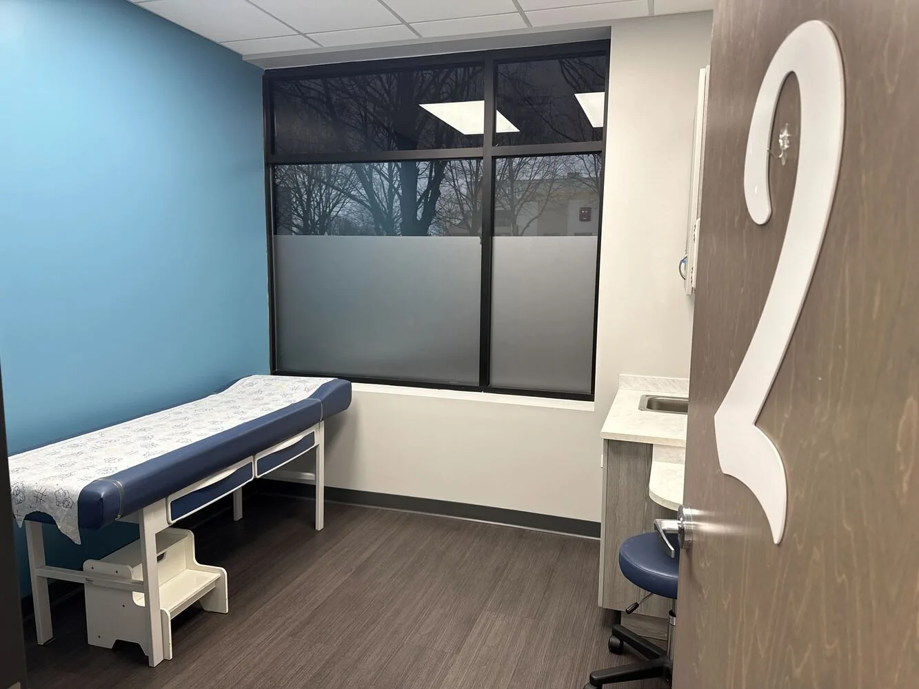 Repainted exam room with a blue accent wall and frosted window
