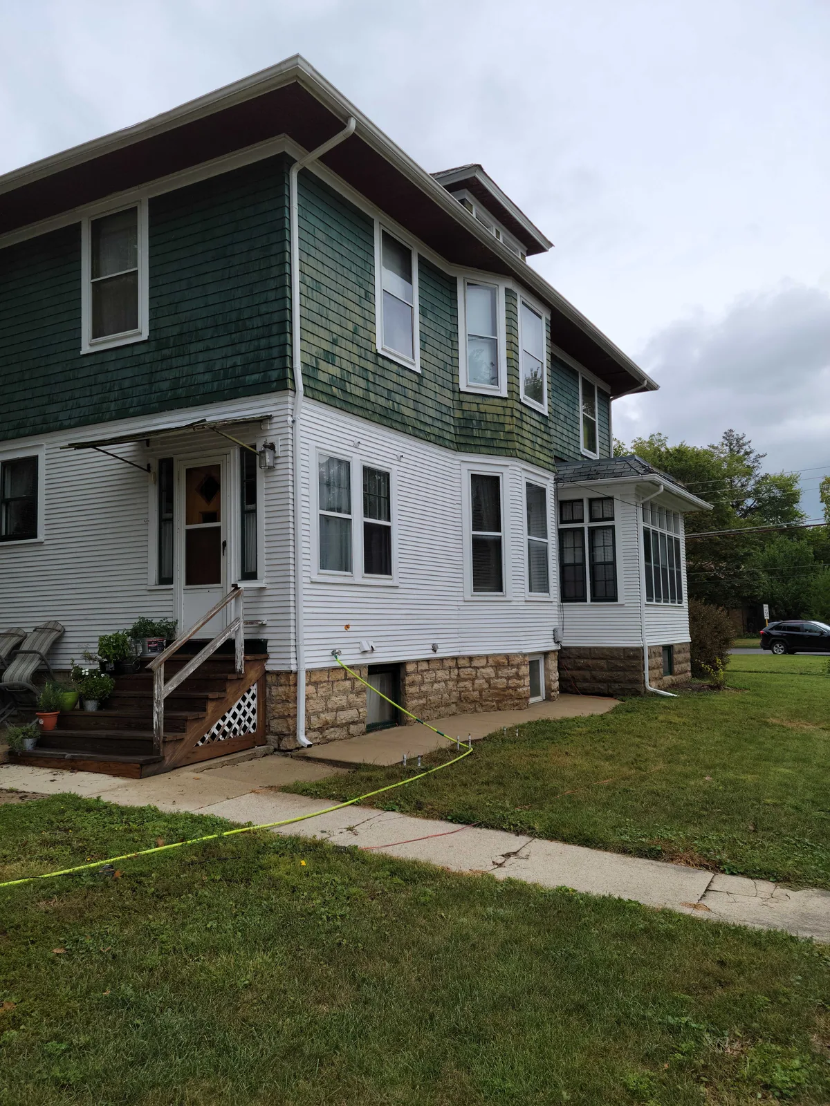 Two story home with dark green siding and white trim