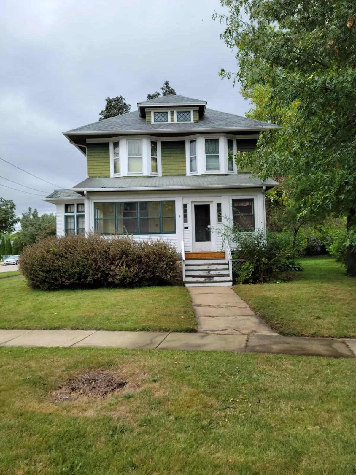 Front elevation of a repainted green craftsman home
