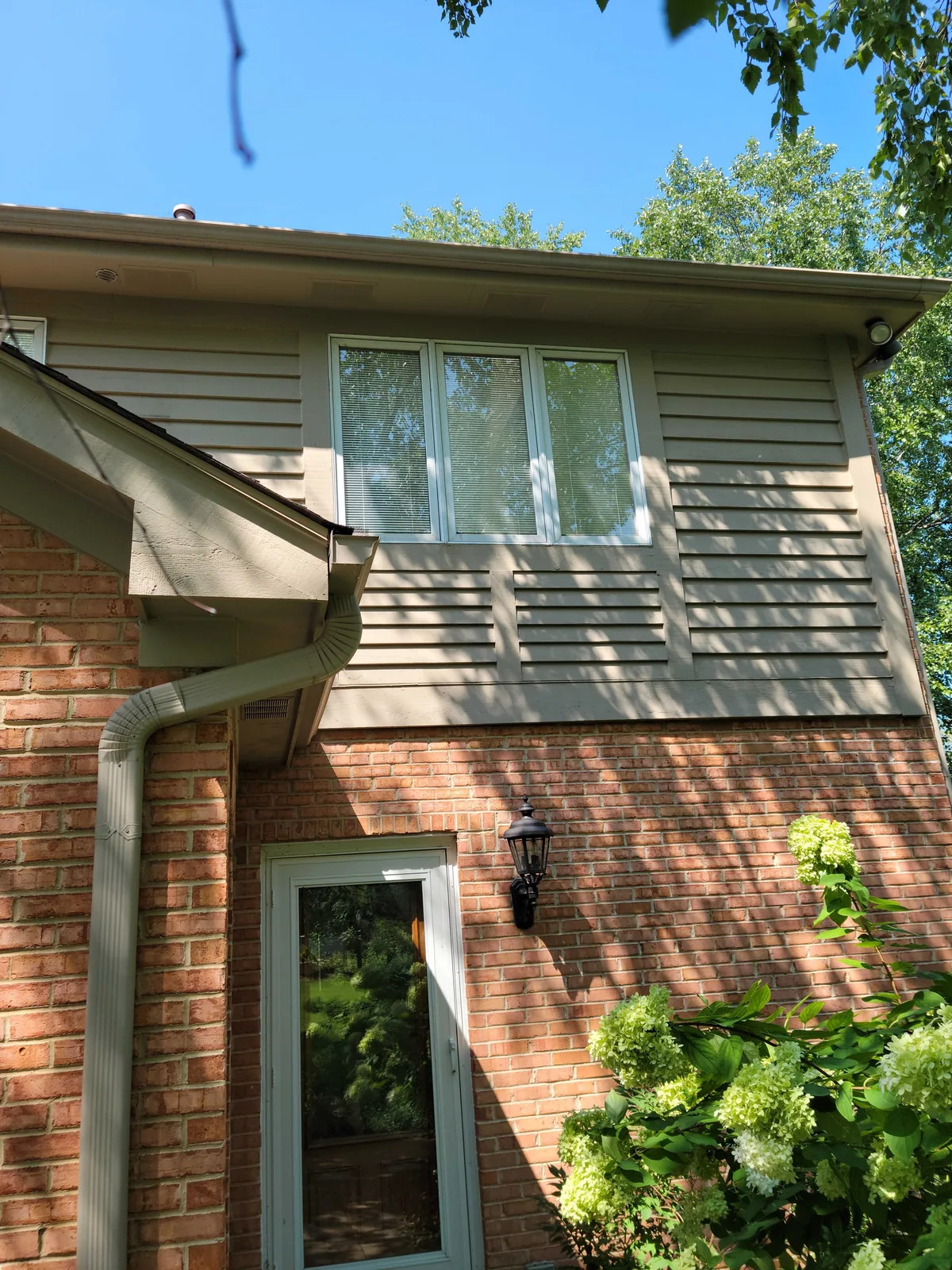 Repainted brick home with cream trim and a green door