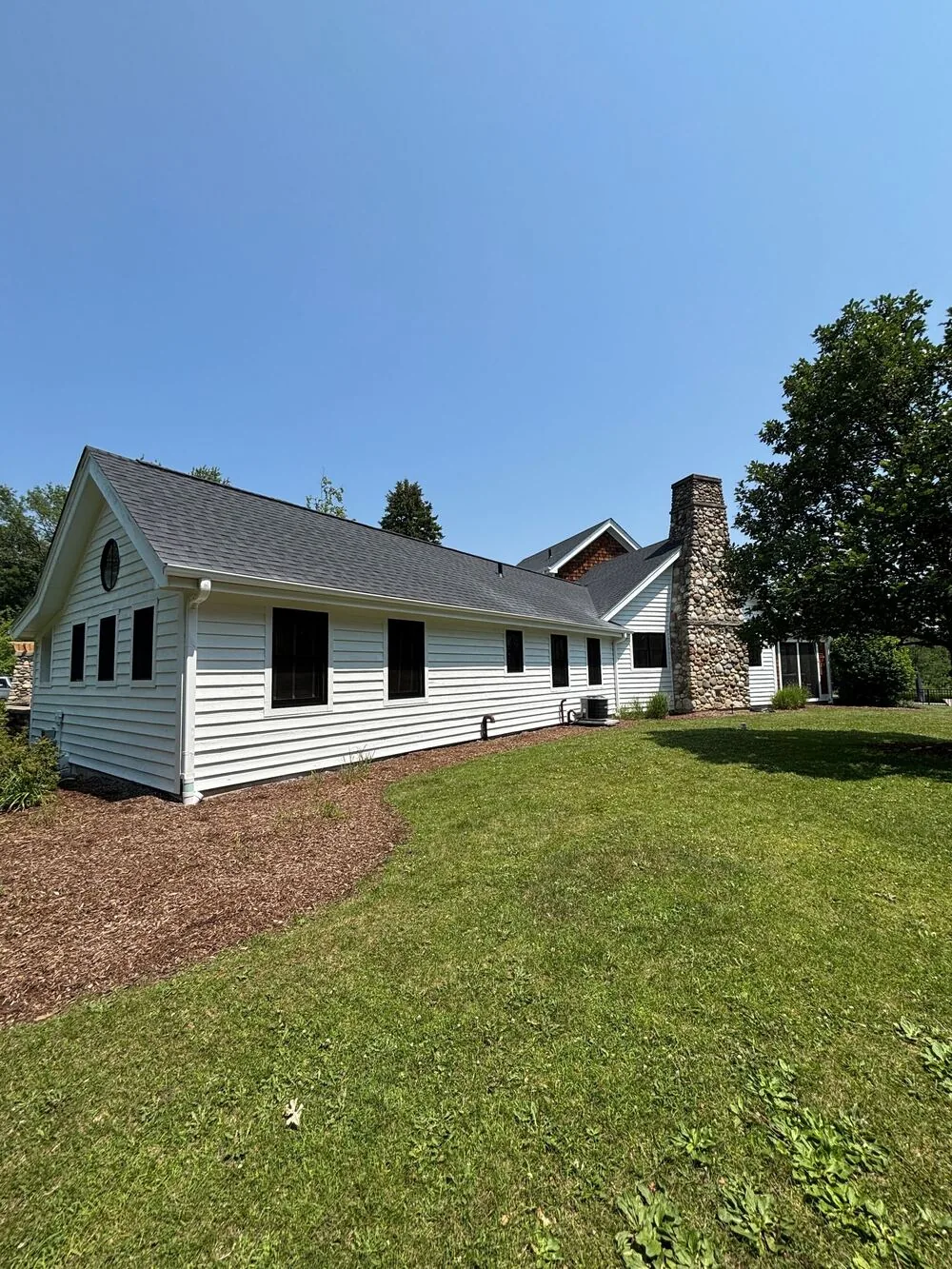 White ranch with black shutters and a stone chimney after an exterior repaint