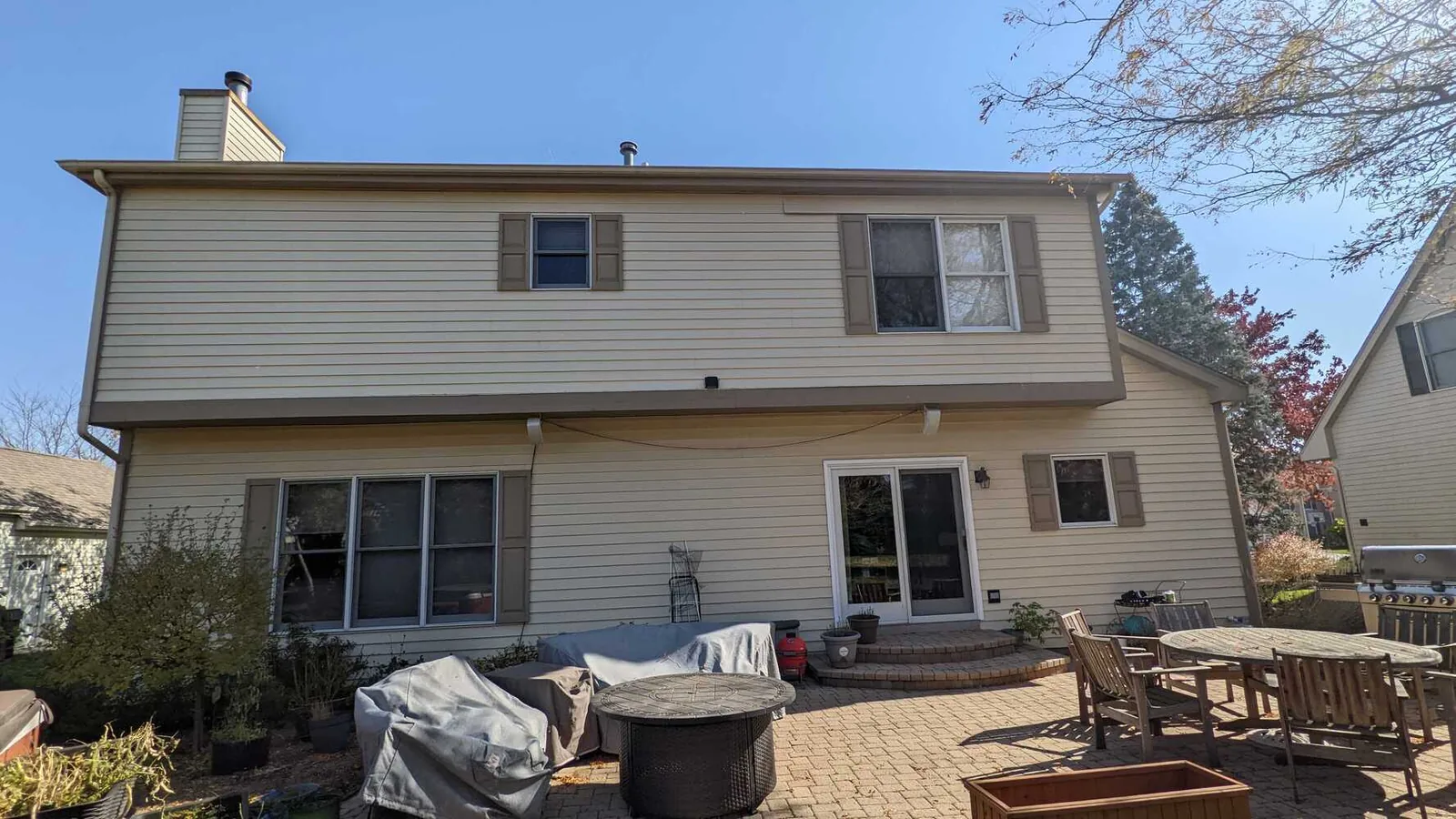 Repainted rear elevation of a two story home with a patio