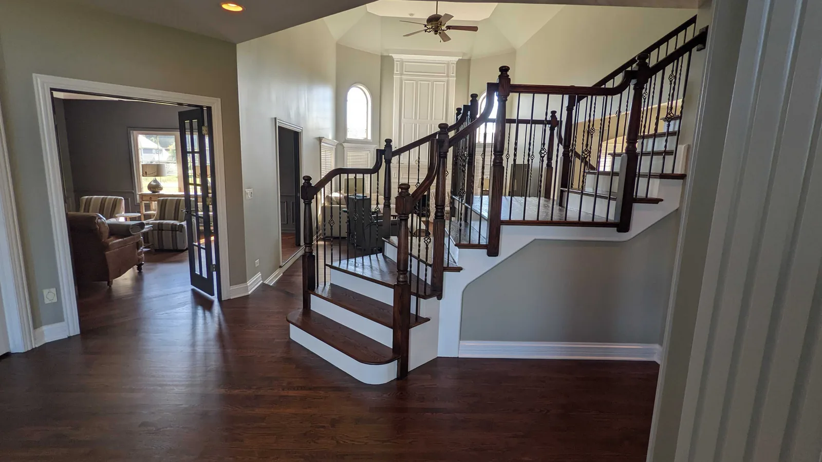 Two story foyer with gray walls and a dark stained staircase