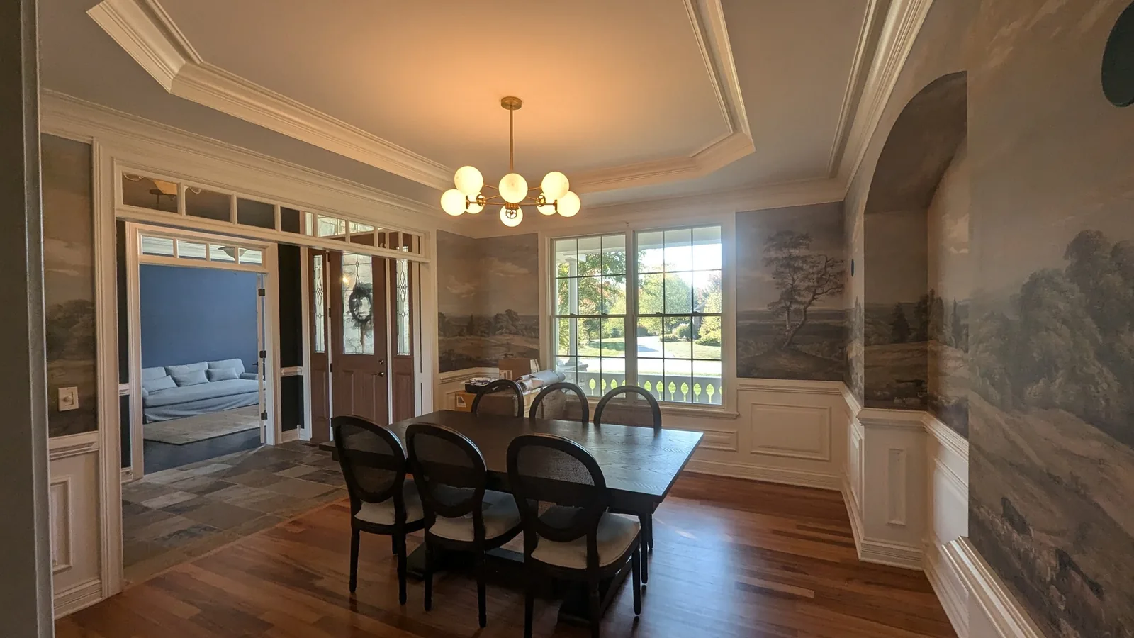 Dining room with a scenic mural and white wainscoting