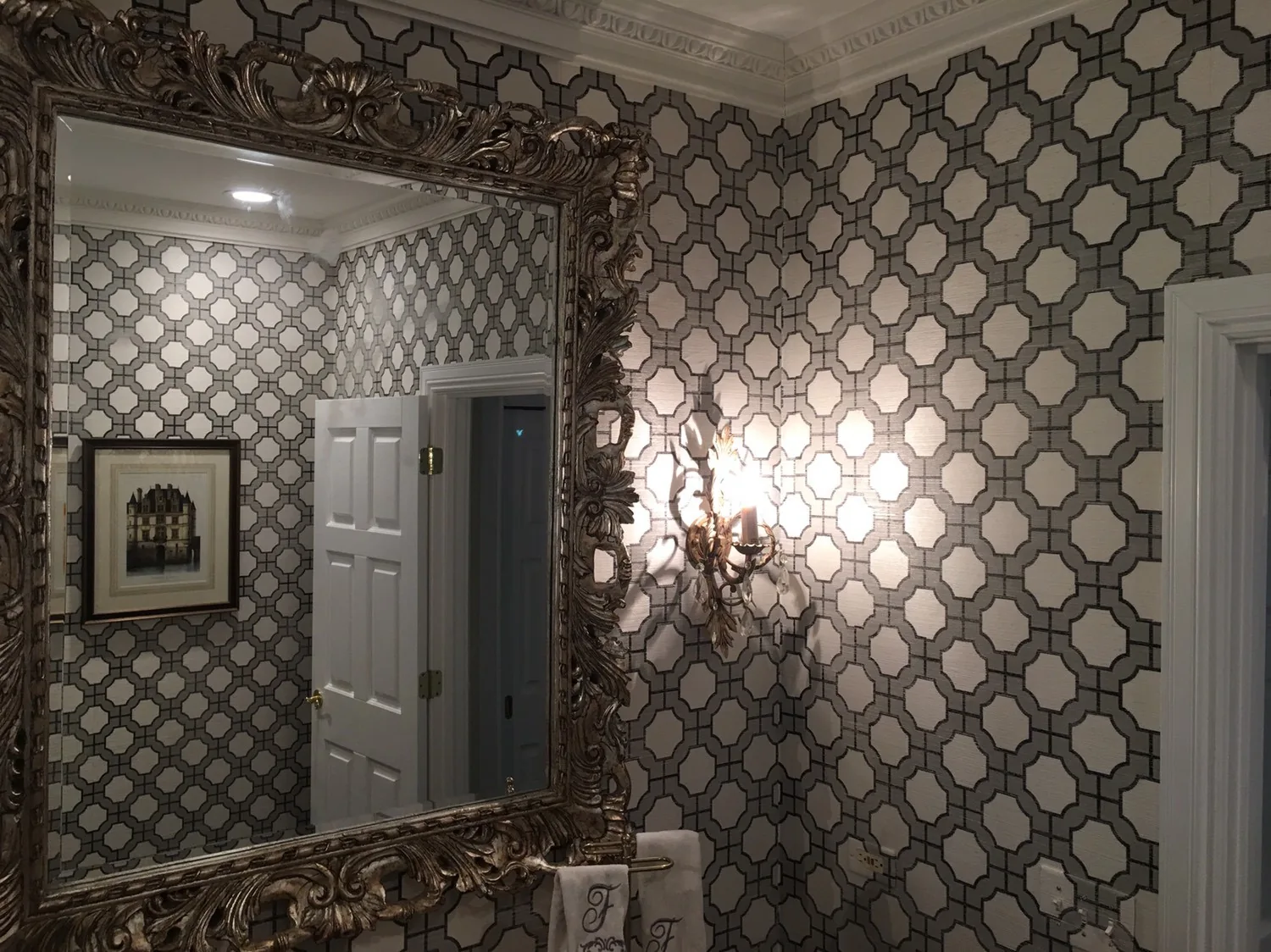 Geometric trellis wallpaper in a powder room with an ornate mirror