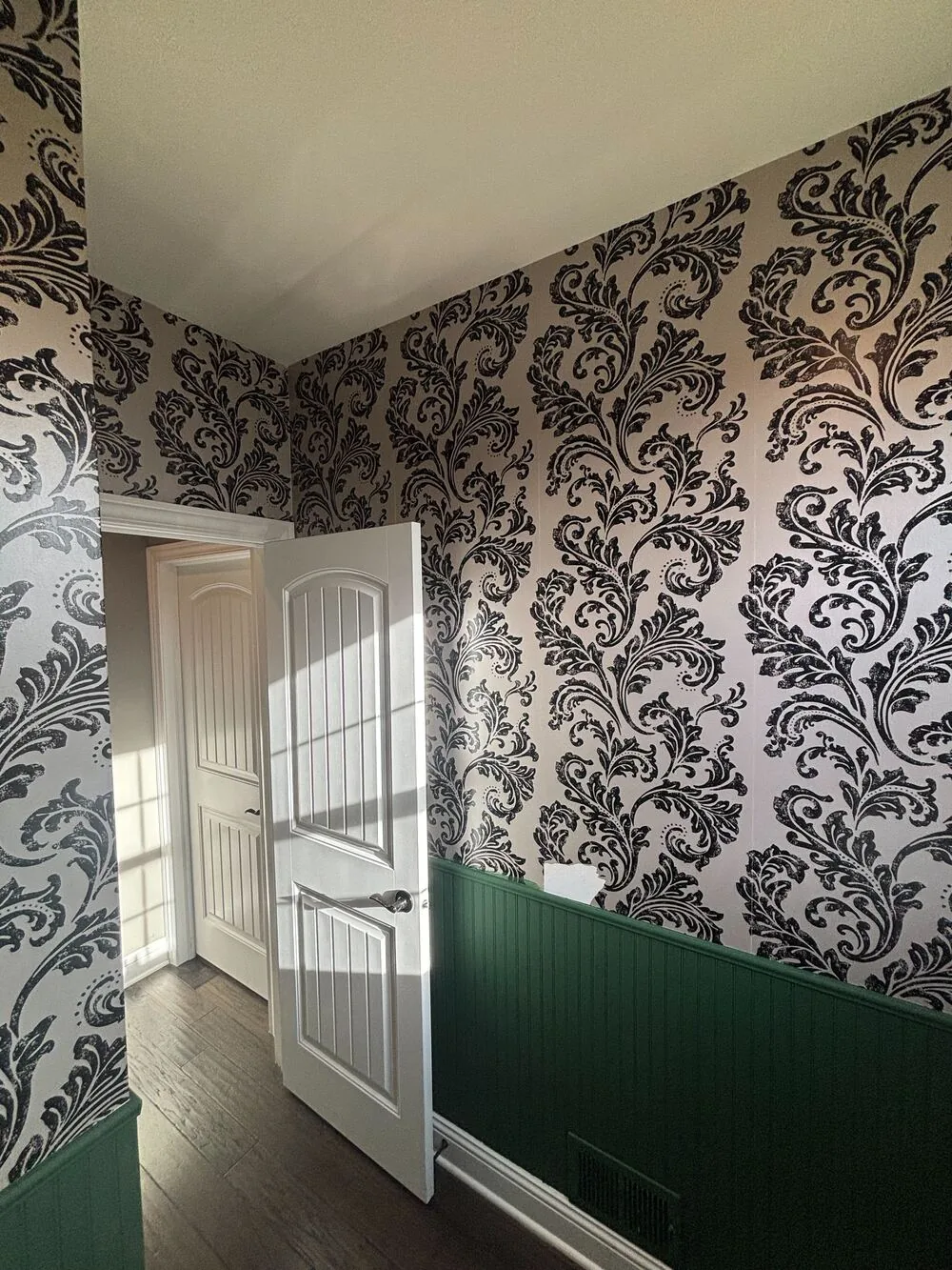 Gray damask wallpaper above green wainscoting